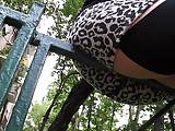 Girl in leopard skirt and stockings sitting on a fence