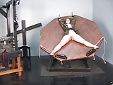 Young blonde slave gets strapped in a spinning wheel